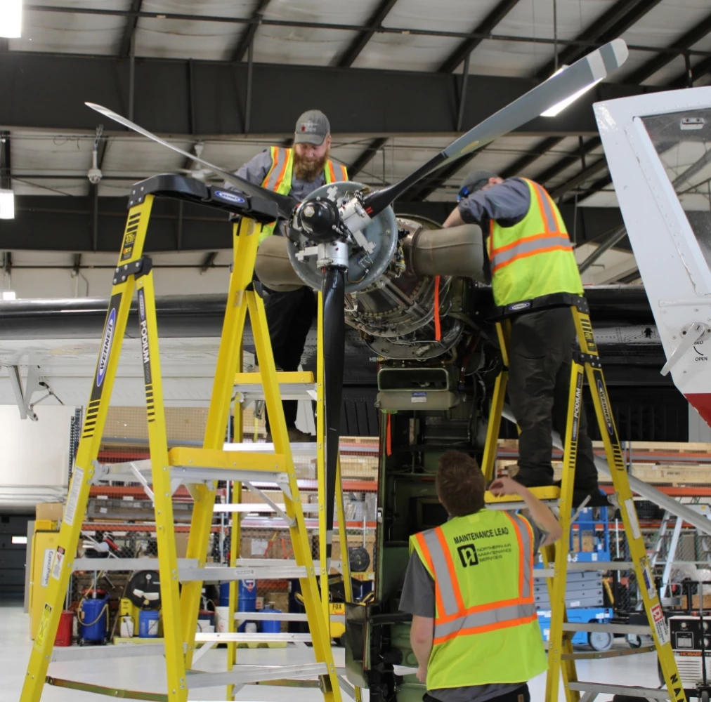 NAMS employees working on the propellor of a plane.