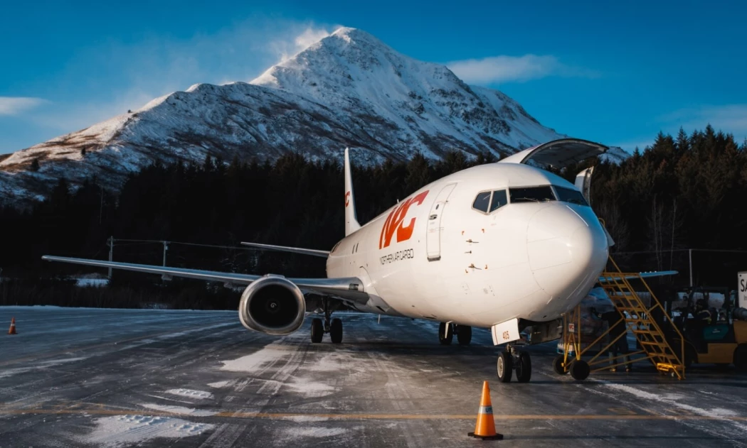 A Northern Air Cargo plane sitting on the runway with a snowcapped mountain in the background.