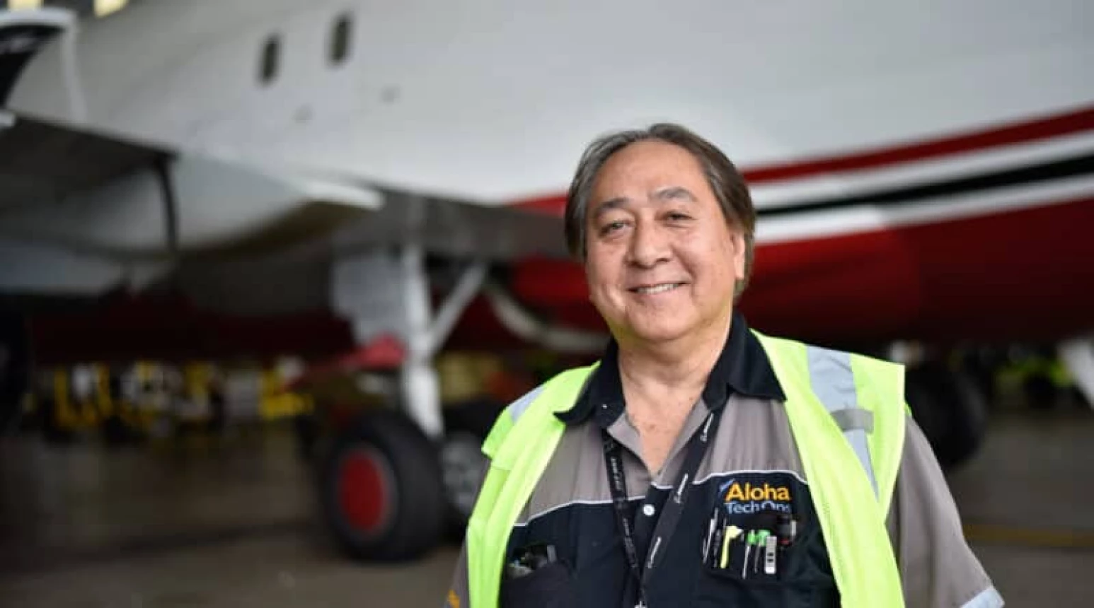 Photo of Aloha Tech Ops employee Darren Espina standing in front of a plane.