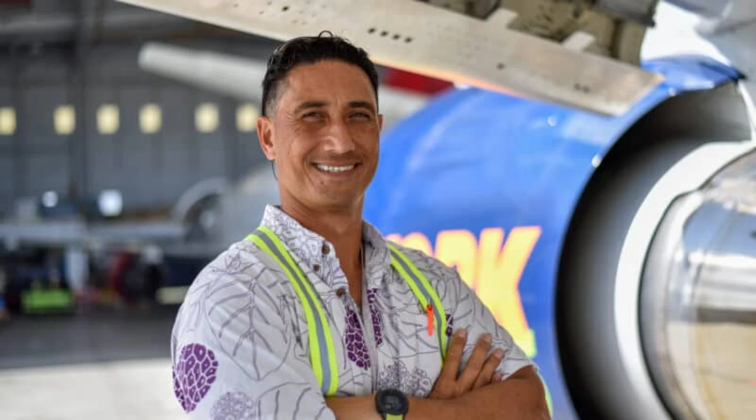 Photo of Aloha Tech Ops employee Mario Mausio standing in front of a plane.