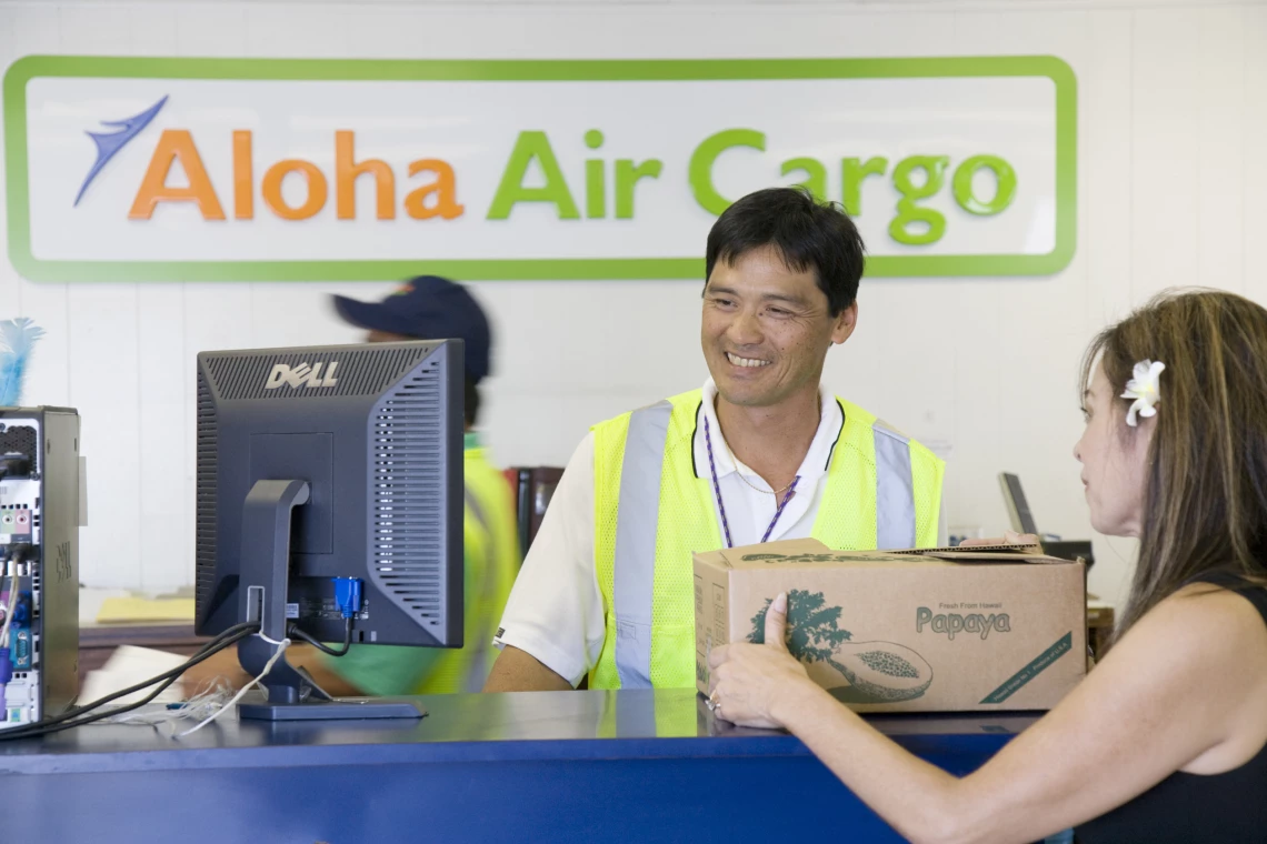 An Aloha Air Cargo customer service agent helping a customer with her package.